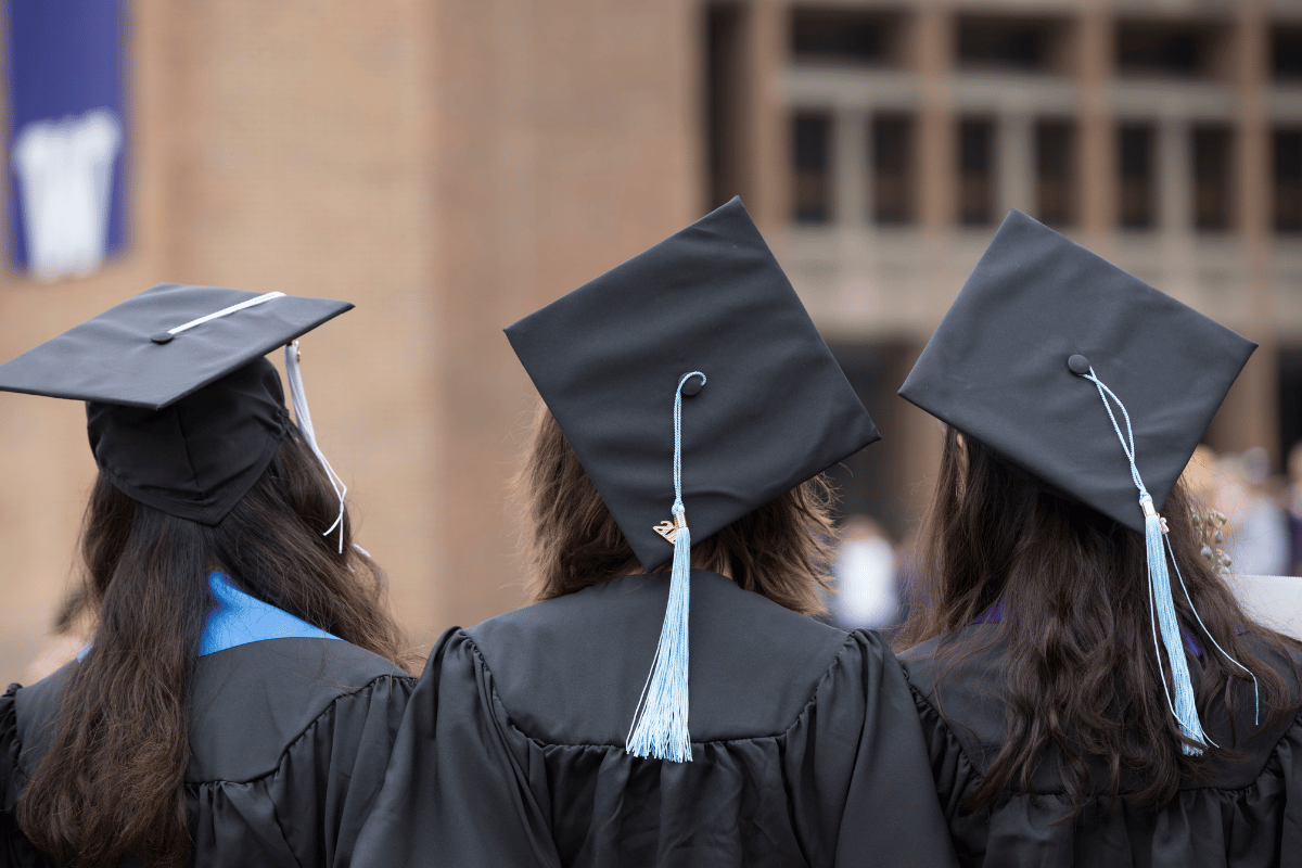 three graduates in cap and gown
